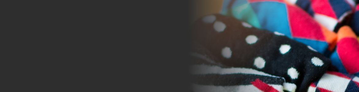 Plusieurs draps contours pliés et regroupés. Certains draps sont noirs avec des pois blancs et d'autres sont multicolores